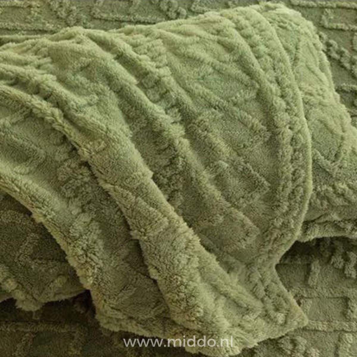 Drap-housse en polaire vert sauge à motif torsadé délicatement drapé sur un lit