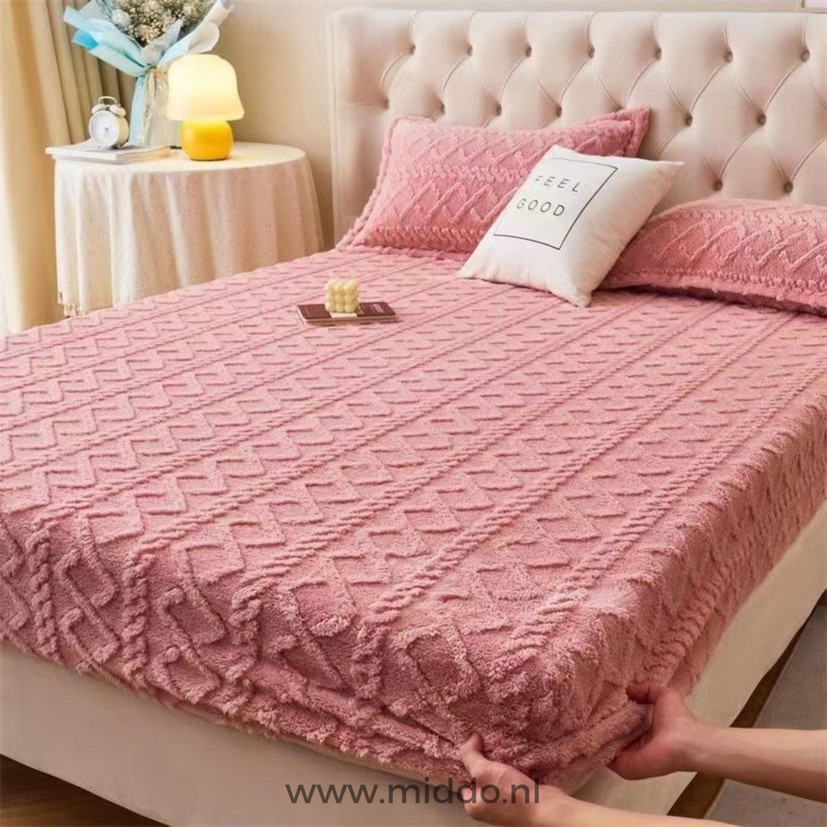 Drap-housse en polaire rose à motif torsadé bien tendu sur un lit avec taies assorties
