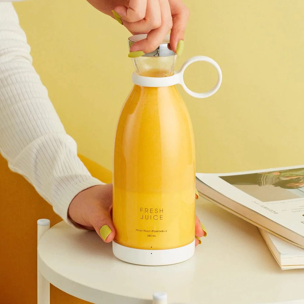 main tenant le blender sans fil rechargeable avec du jus d'orange fraîchement pressé