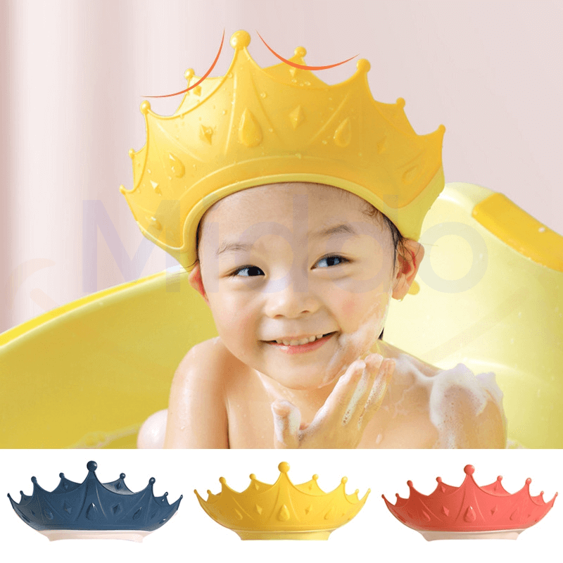 enfant souriant dans le bain avec un bonnet de douche couronne jaune protégeant les yeux
