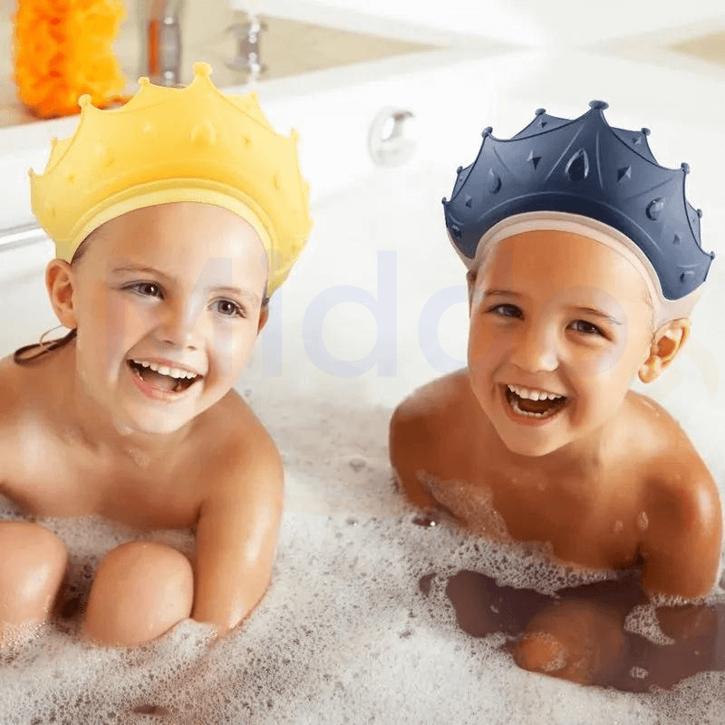 deux enfants souriants dans le bain portant des bonnets de douche en forme de couronne jaune et bleue