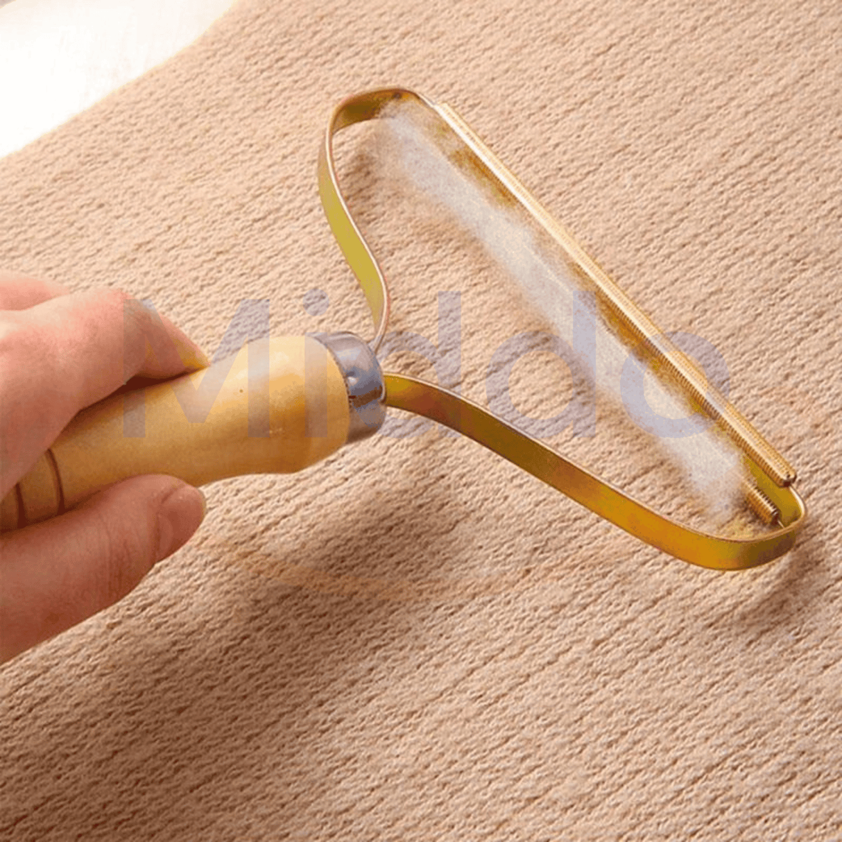 main tenant le furbuster qui retire peluches et poils d'une surface en tissu
