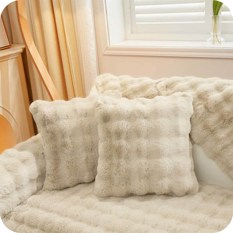coussins et plaid blancs moelleux sur un canapé clair pour une déco lumineuse et douce