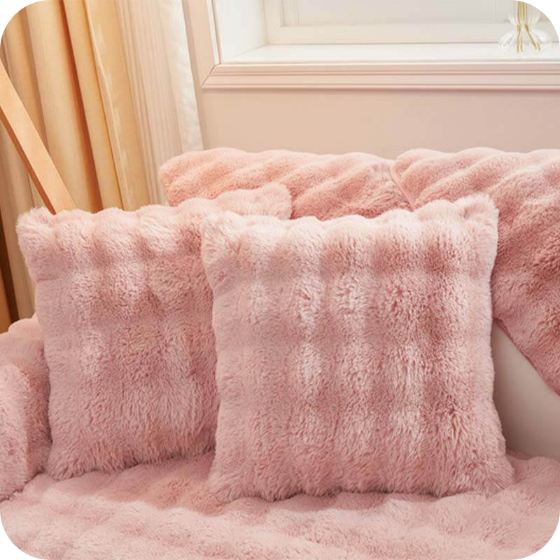 coussins et plaid roses moelleux sur un canapé près d'une fenêtre, ambiance douce et féminine