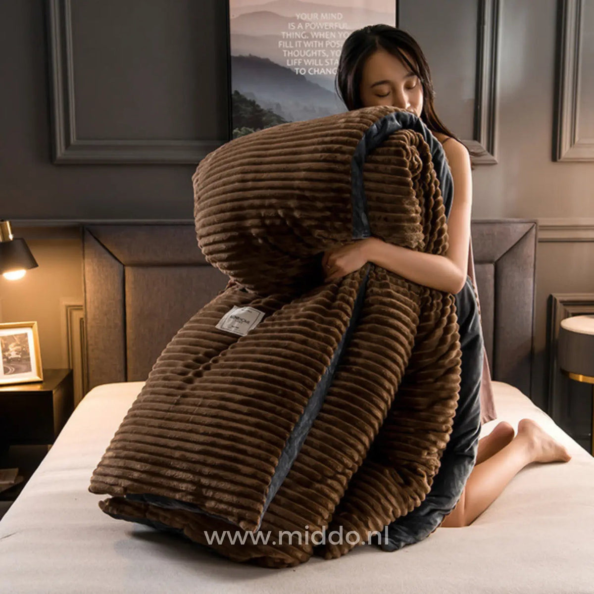 Femme tenant une housse de couette en velours polaire brun à texture côtelée et bordure foncée