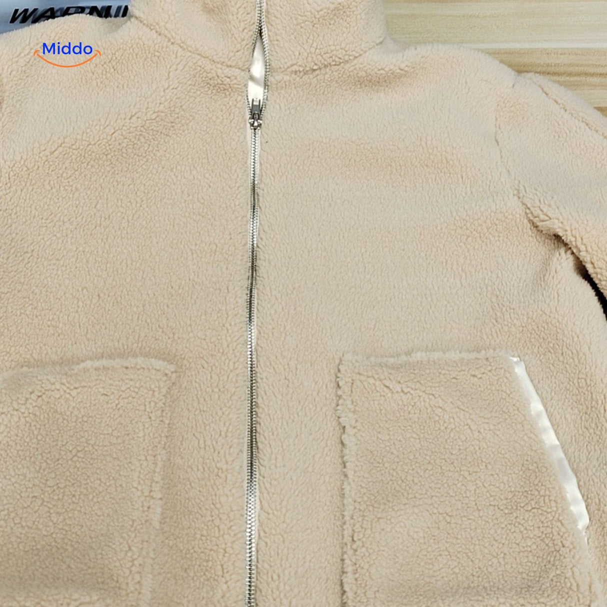 manteau teddy beige sur fond blanc, présentation épurée de la coupe et du coloris