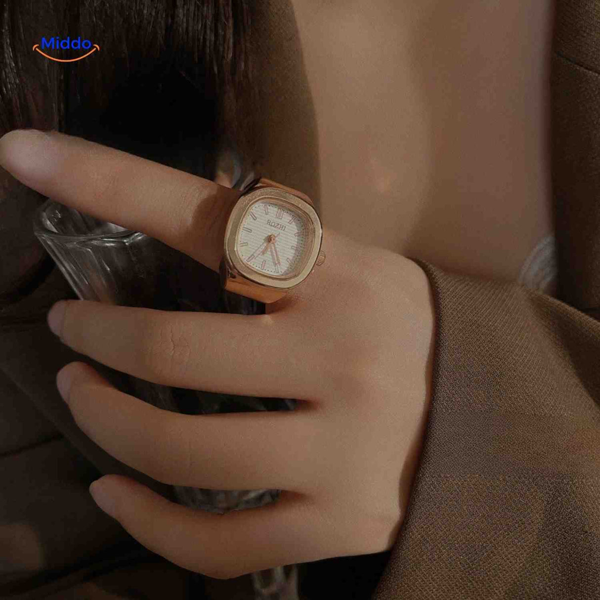 montre-bague rose avec cadran blanc portée sur une main, look féminin délicat