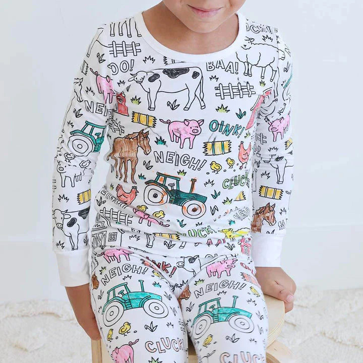 garçon portant un pyjama à colorier motif ferme avec les dessins qu'il a lui-même colorés