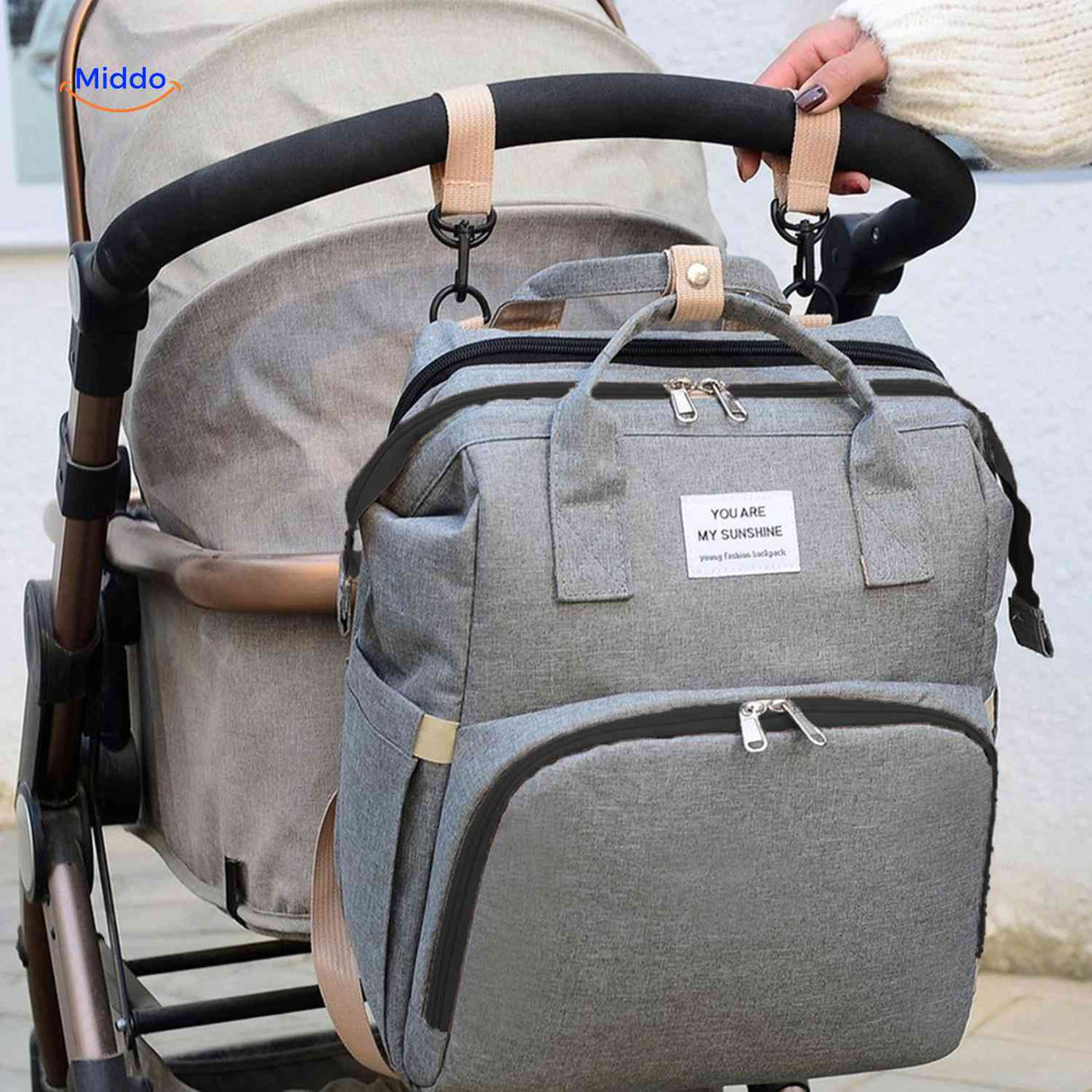 sac à langer gris accroché à une poussette grâce aux crochets de fixation inclus
