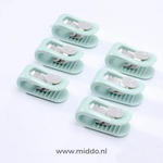 Zes groene dekbedklemmen op witte achtergrond