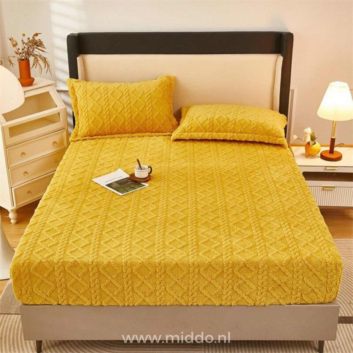 Drap-housse en polaire jaune ocre à motif torsadé bien tendu sur un lit, avec deux taies assorties