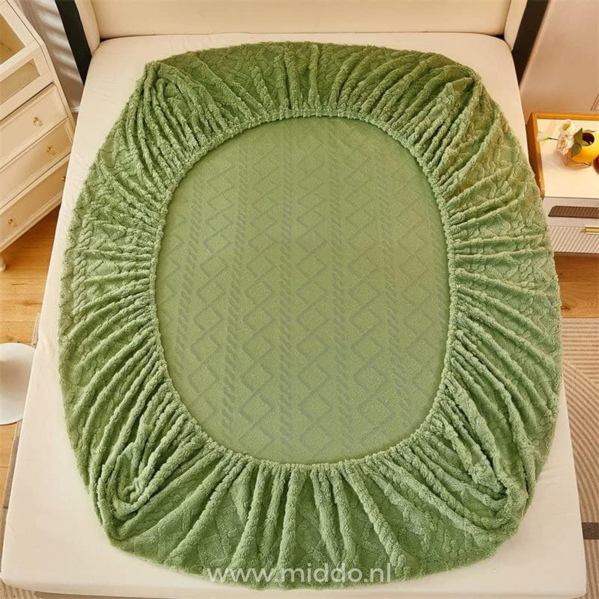 Vue de dessus du drap-housse en polaire vert sauge maintenu autour du matelas par son bord élastique