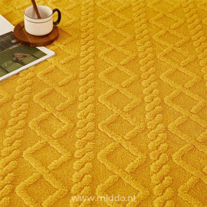 Gros plan sur un drap-housse en polaire jaune ocre avec une tasse de café et un magazine