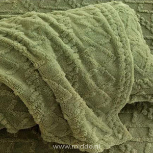 Drap-housse en polaire vert sauge à motif torsadé délicatement drapé sur un lit