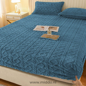 Drap-housse en polaire bleu à motif torsadé bien tendu sur un lit avec taies assorties