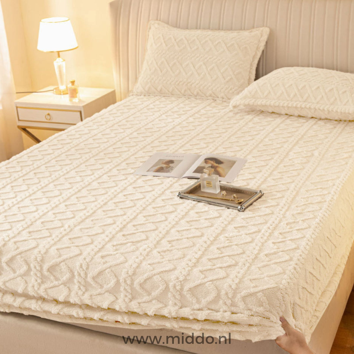 Drap-housse en polaire blanc crème à motif torsadé bien tendu sur un lit avec taies assorties