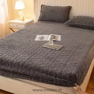 Drap-housse en polaire gris foncé à motif torsadé bien tendu sur un lit avec taies assorties