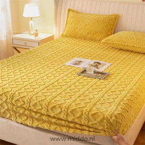 Drap-housse en polaire jaune à motif torsadé bien tendu sur un lit avec taies assorties