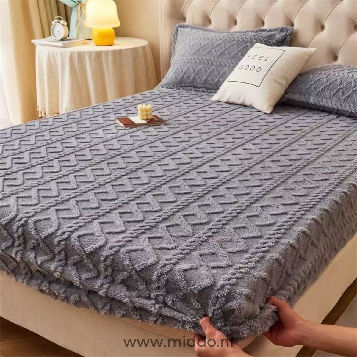 Drap-housse en polaire gris à motif torsadé bien tendu sur un lit avec taies assorties