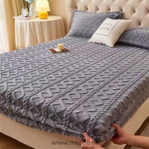 Drap-housse en polaire gris à motif torsadé bien tendu sur un lit avec taies assorties