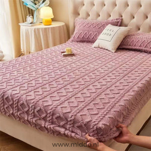 Drap-housse en polaire vieux rose à motif torsadé bien tendu sur un lit avec taies assorties