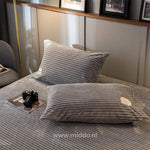 2 kussens met grijze kussenslopen op een bed