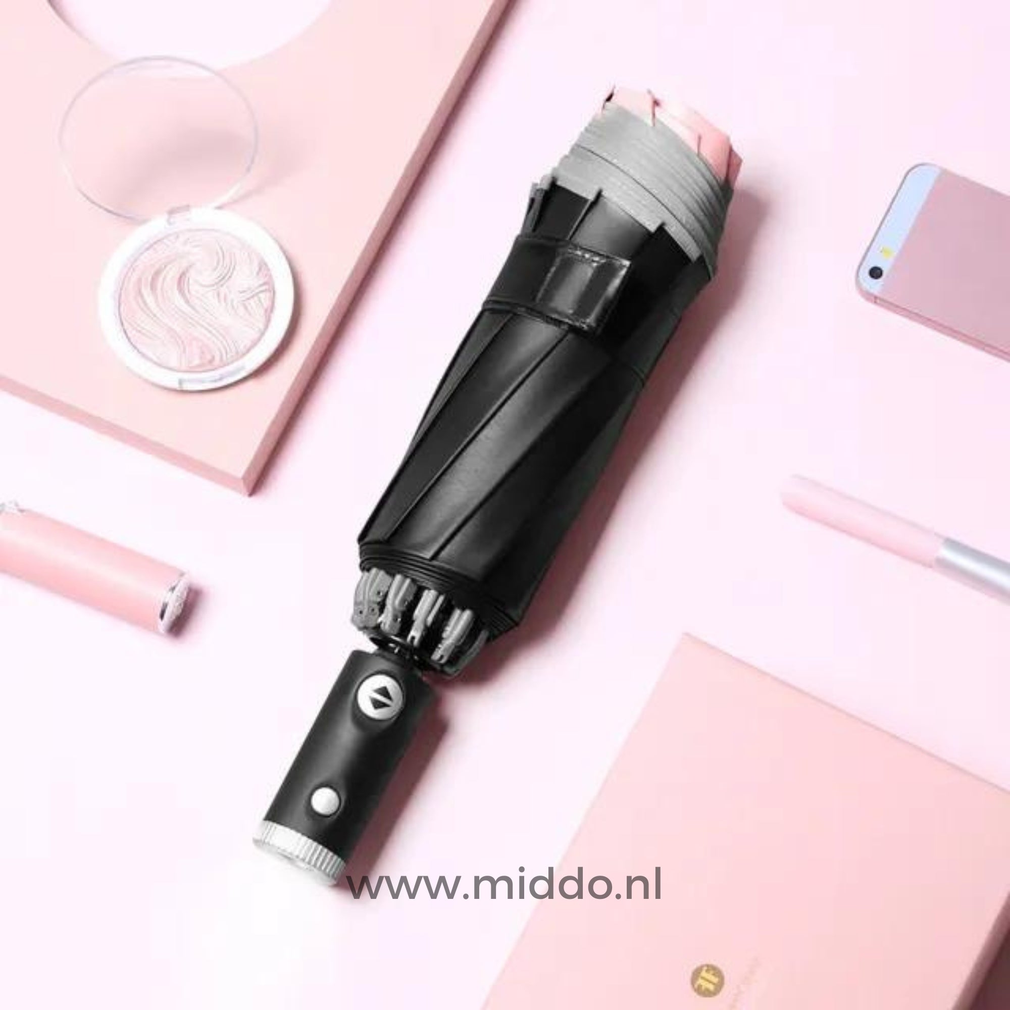 Zwarte paraplu met reflecterende rand met mobiel en pen op roze achtergrond.