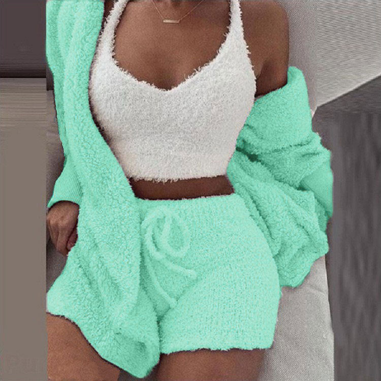 Vrouw in mintkleurige SheCutie comfy set met short, top en vest zittend op bank
