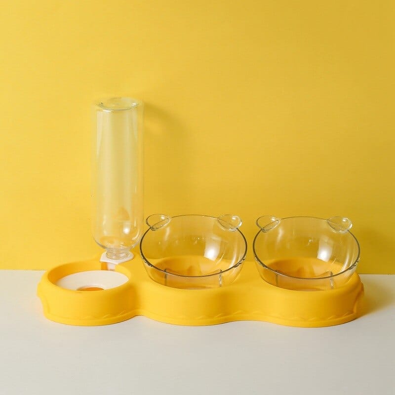 Gele voedertray met voerbakken en waterdispenser.