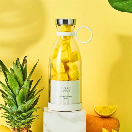 blender sans fil rempli d'ananas frais entouré d'un assortiment de fruits tropicaux