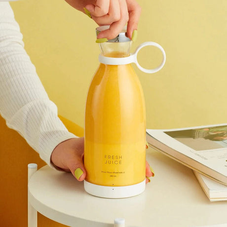 main tenant le blender sans fil rechargeable avec du jus d'orange fraîchement pressé