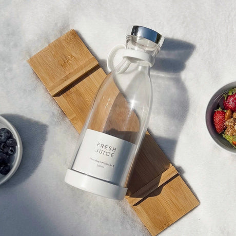 blender sans fil posé sur une nappe de pique-nique entouré de fruits frais et de granola