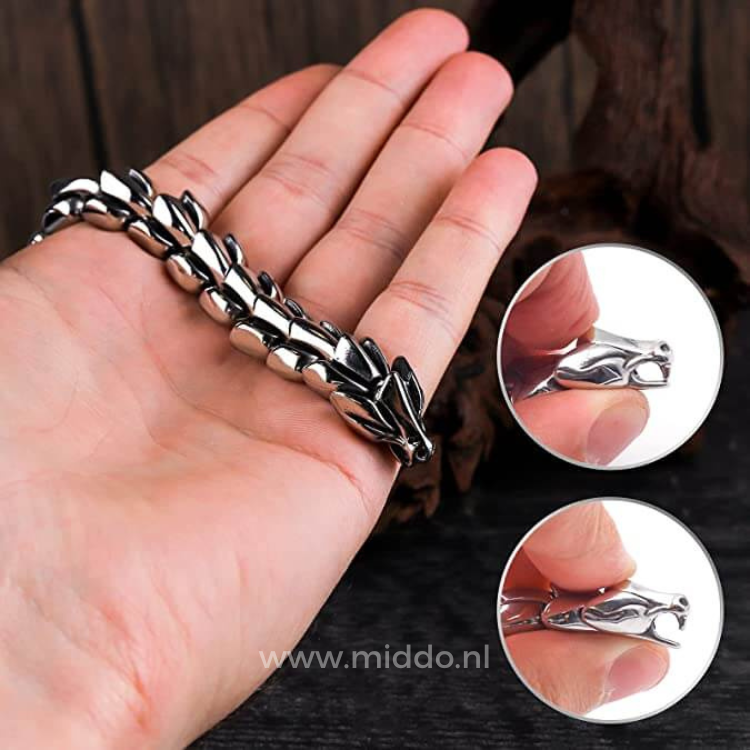 gros plan sur une main tenant un bracelet dragon argent, détail de la tête de dragon et des maillons