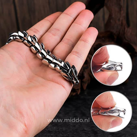 gros plan sur une main tenant un bracelet dragon argent, détail de la tête de dragon et des maillons
