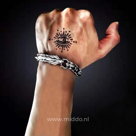 main tatouée portant un bracelet dragon viking argent, détail du motif nordique
