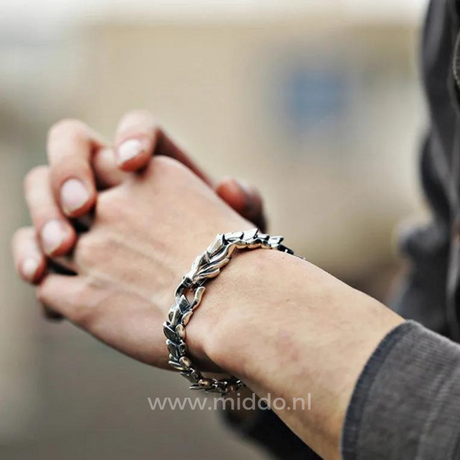 personne aux mains jointes portant un bracelet dragon viking argent, prise de vue en extérieur
