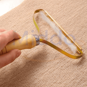 main tenant le furbuster qui retire peluches et poils d'une surface en tissu