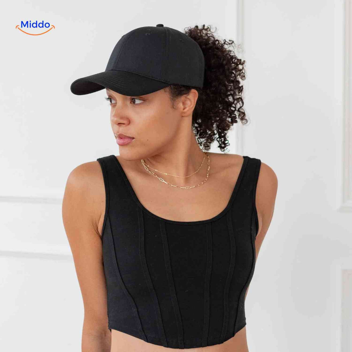 casquette ponytail noire portée avec des cheveux bouclés, style féminin tendance