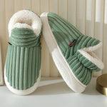 chaussons verts en fluffy fleece avec doublure blanche posés devant un rideau beige