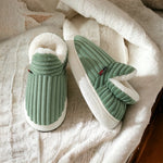 chaussons verts en fluffy fleece avec doublure blanche posés sur un tapis blanc doux