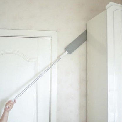 chiffon extensible glissé derrière une armoire pour un nettoyage en profondeur