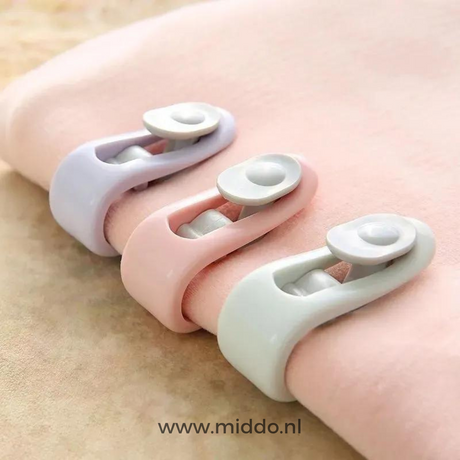 trois clips pour couette en teintes pastel posés sur une couverture douce