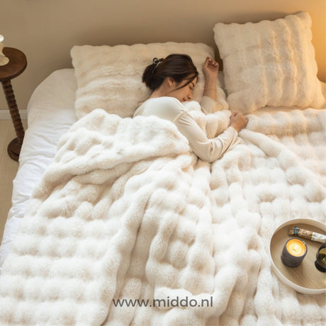 personne endormie sous une couverture toison toscane dans une chambre aux tons beiges