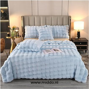 couverture d'hiver toison toscane bleu clair drapée sur un lit avec coussins décoratifs