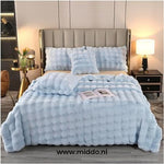 couverture d'hiver toison toscane bleu clair drapée sur un lit avec coussins décoratifs