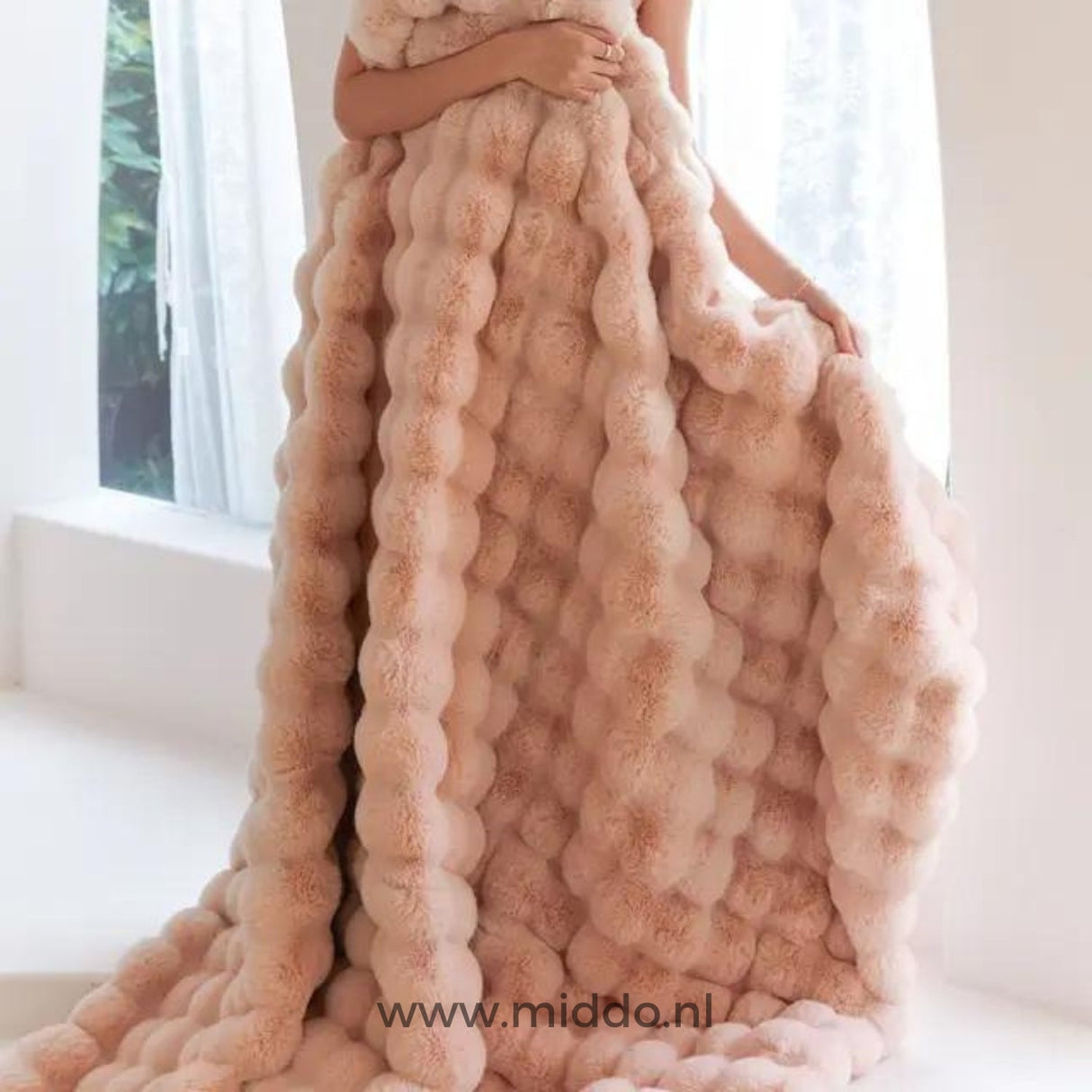 femme enveloppée dans une couverture toscane rose fluffy près d'une fenêtre lumineuse