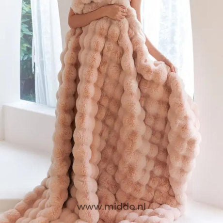 femme enveloppée dans une couverture toscane rose fluffy près d'une fenêtre lumineuse