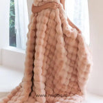 femme enveloppée dans une couverture toscane rose fluffy près d'une fenêtre lumineuse