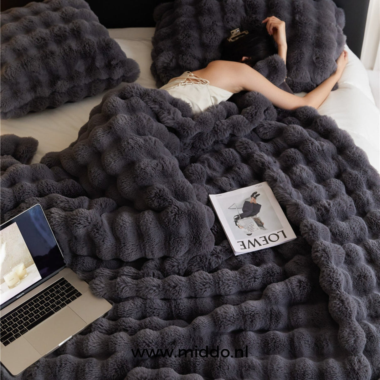 couverture d'hiver toscane noire sur un lit avec magazine et ordinateur portable
