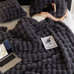 couverture d'hiver toscane noire sur un lit avec magazine et ordinateur portable